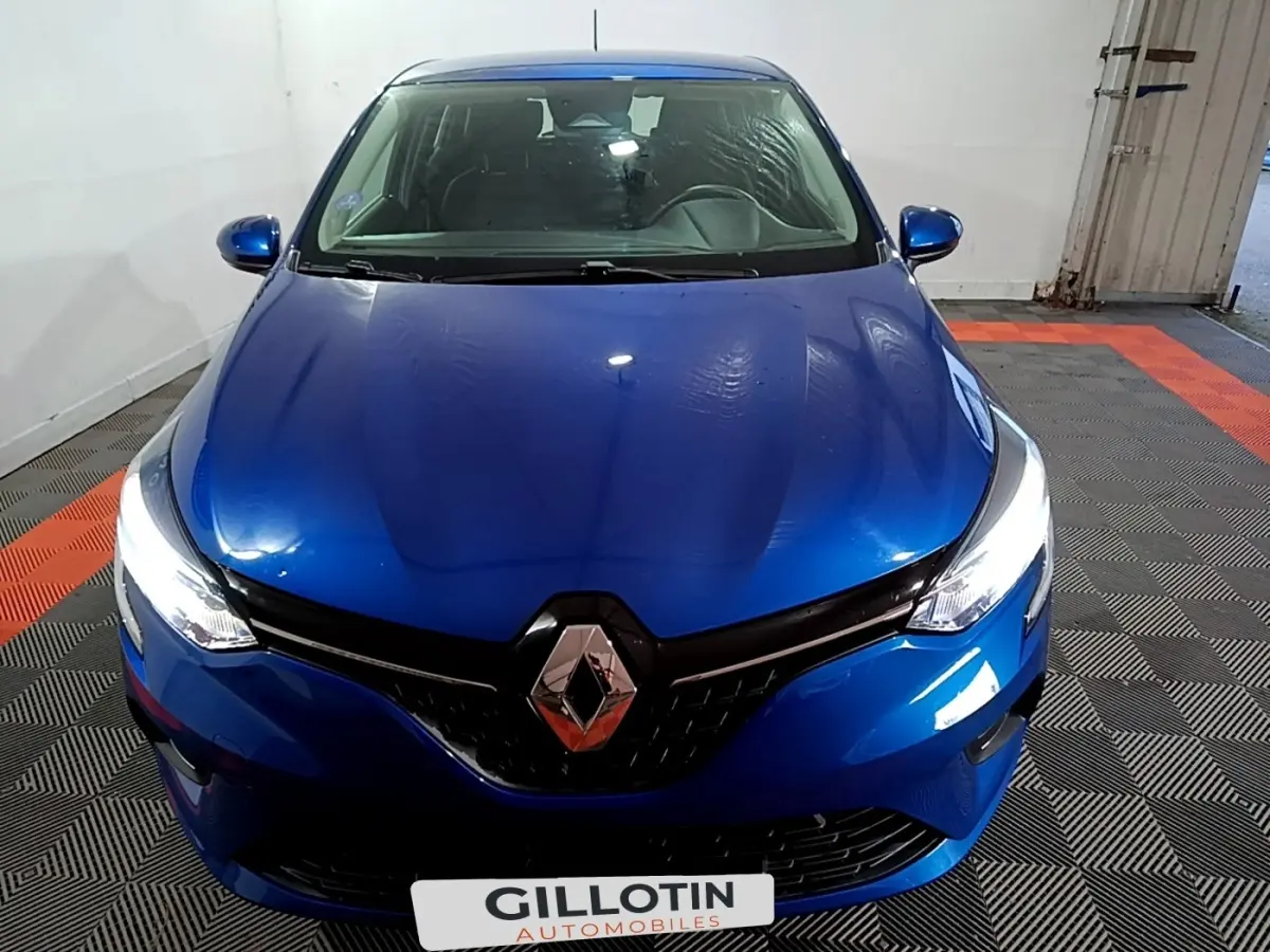 Vue avant rapprochée d’une Renault Clio Business bleu, avec phares LED allumés et logo Renault central bien visible.