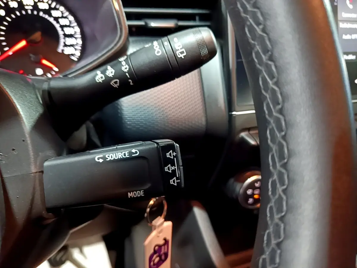 Gros plan sur le volant cuir synthétique et les commandes au volant de la Renault Clio Business bleu, tableau de bord en arrière-plan.