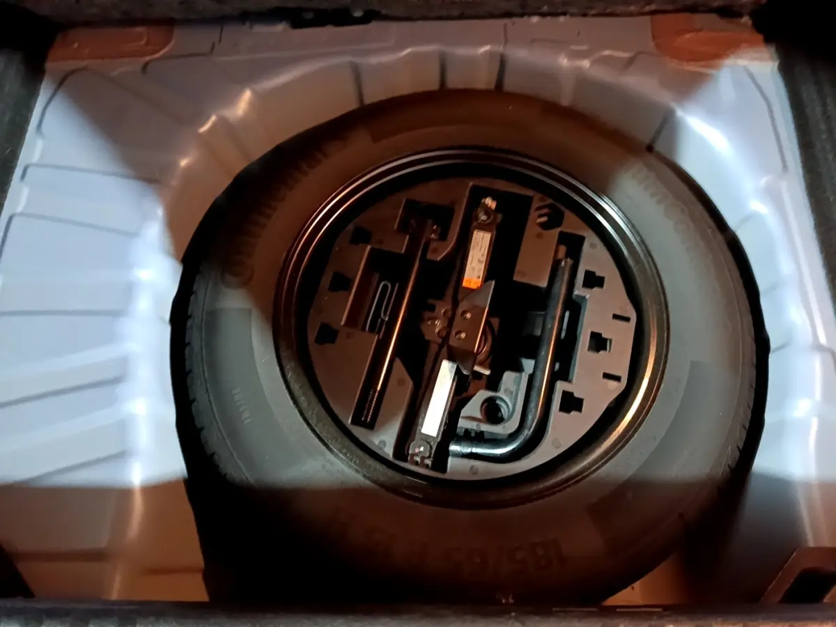 Vue rapprochée de la roue de secours et des outils de bord dans le coffre d’une Renault Clio Business bleu.