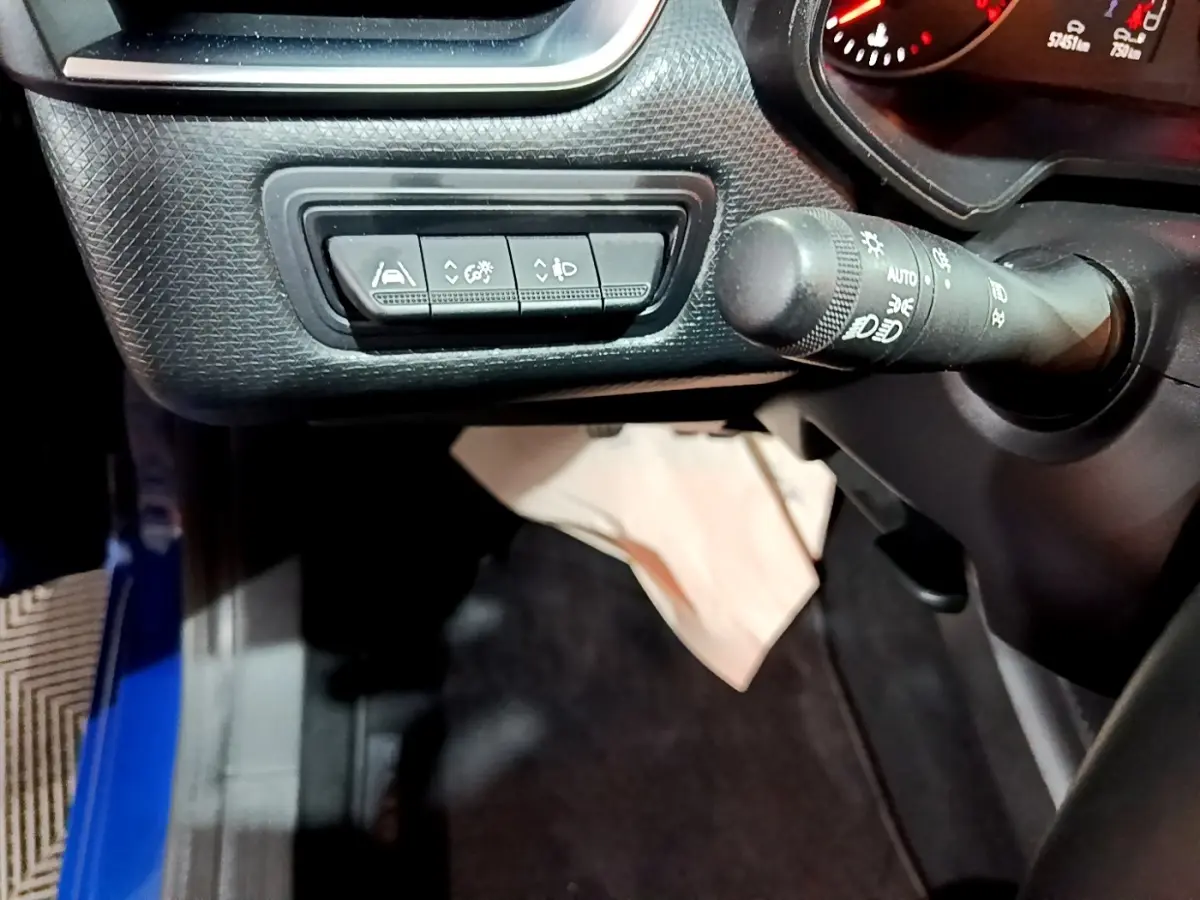 Vue intérieure côté gauche du tableau de bord bleu de la Renault Clio 2022 avec commandes d'assistance et commodo des phares.