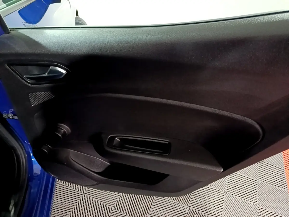 Vue intérieure de la porte côté gauche d'une Renault Clio Business bleu 2022, avec poignée et commande de vitre manuelle.