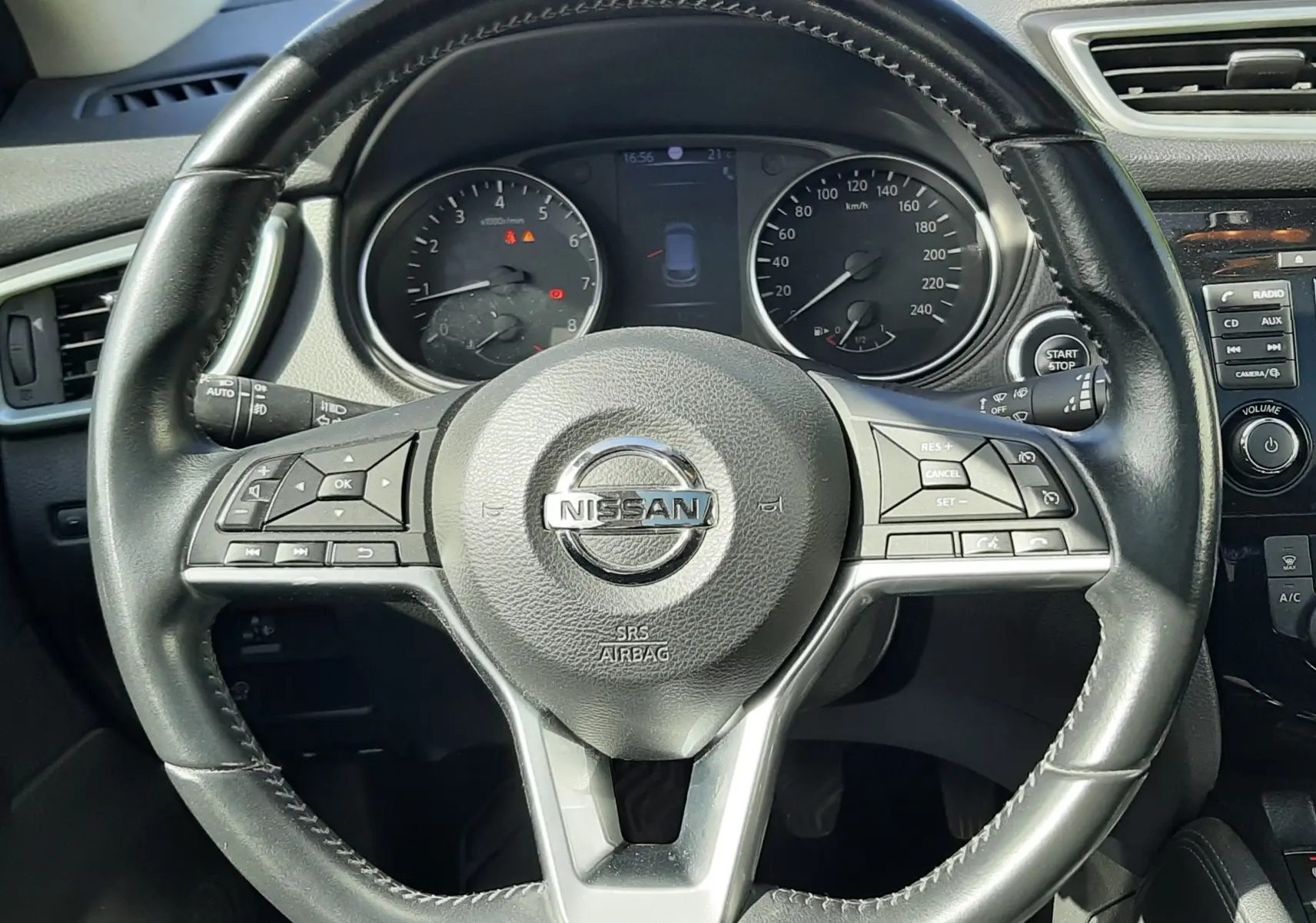 Vue intérieure centrée sur le volant en cuir noir du Nissan Qashqai 2018, avec tableau de bord et commandes visibles.