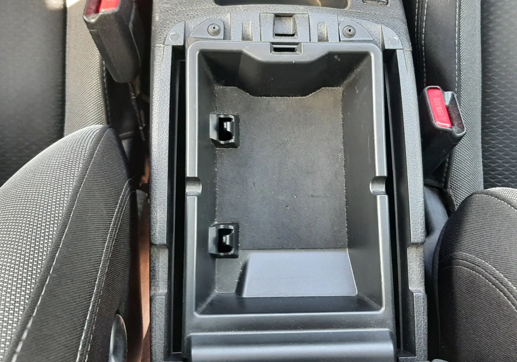 Vue plongeante sur le rangement central ouvert entre les sièges avant en tissu gris noir du Nissan Qashqai 2018.