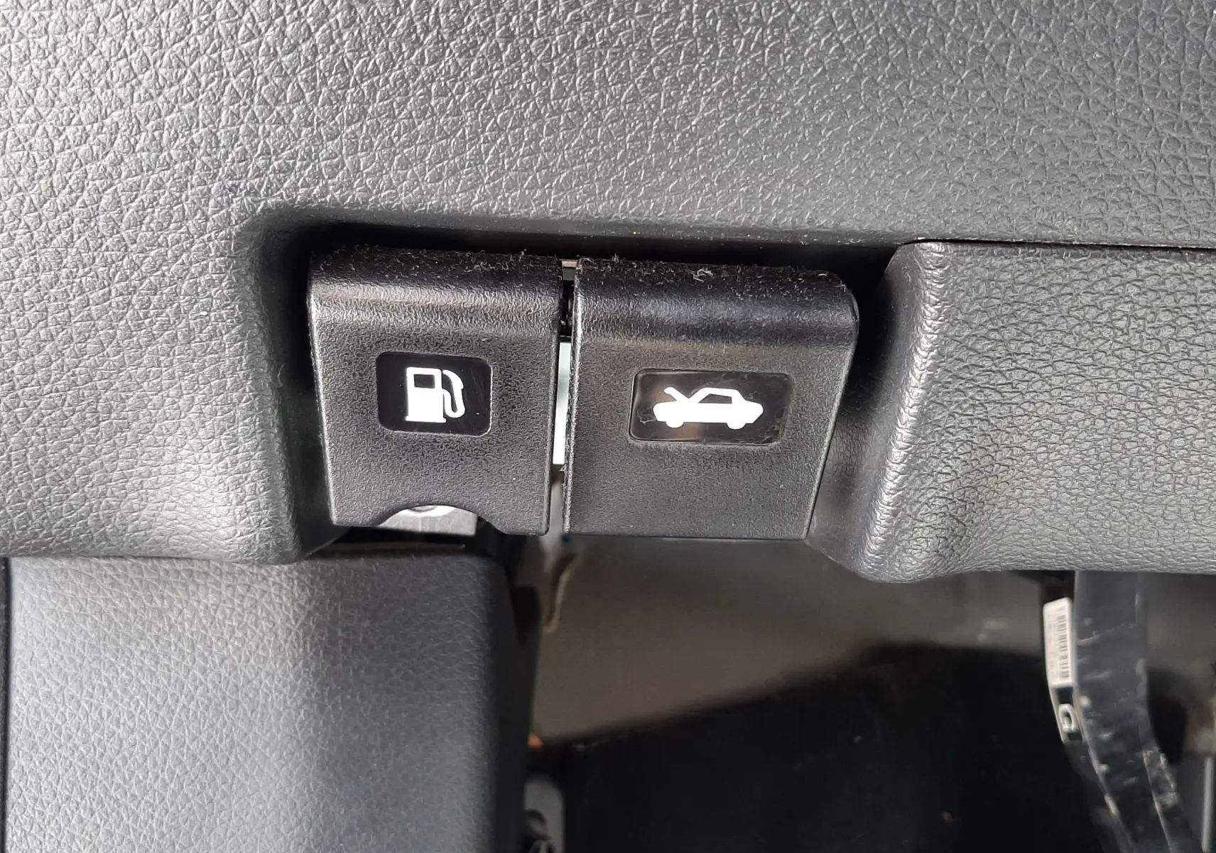 Boutons d'ouverture du capot et de la trappe à carburant sur le tableau de bord intérieur du Nissan Qashqai marron métal 2018.