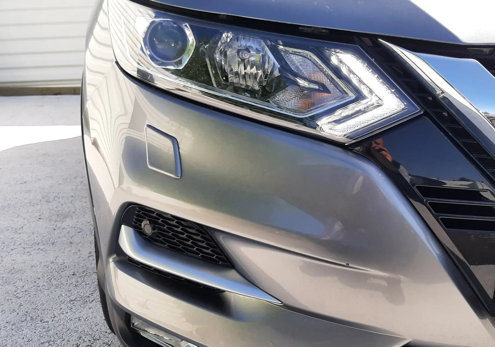 Gros plan sur l'avant droit du Nissan Qashqai marron métal, mettant en valeur le phare LED et la calandre chromée.