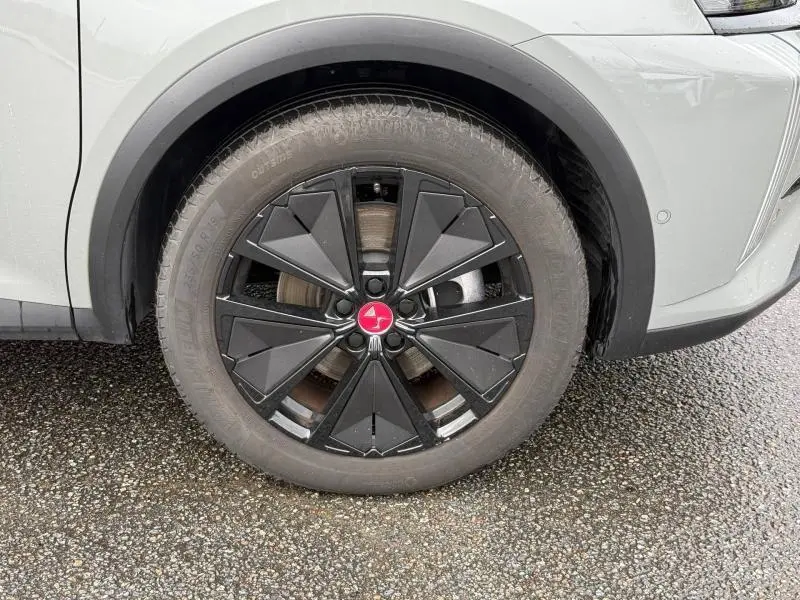 Gros plan sur la roue avant droite du DS7 E-TENSE 225ch gris 2024, avec jante noire au design géométrique distinctif.