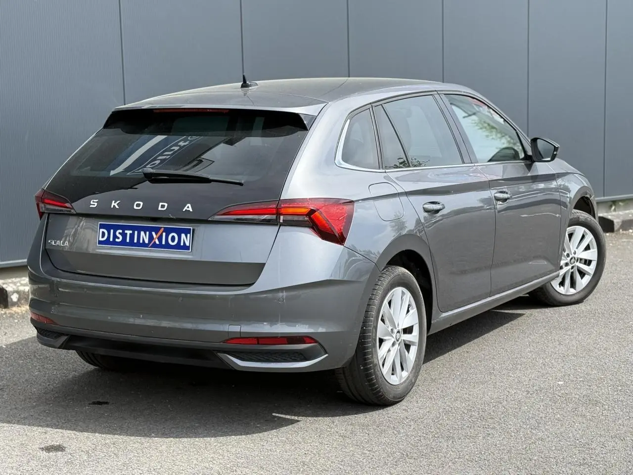 Vue 3/4 arrière droite d'une Skoda Scala gris graphite avec vitres arrière surteintées et jantes alliage 16 pouces.