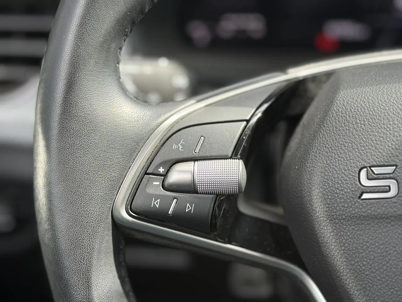 Gros plan sur le volant cuir de la Skoda Scala TSI 116 gris graphite, avec commandes audio intégrées à gauche.