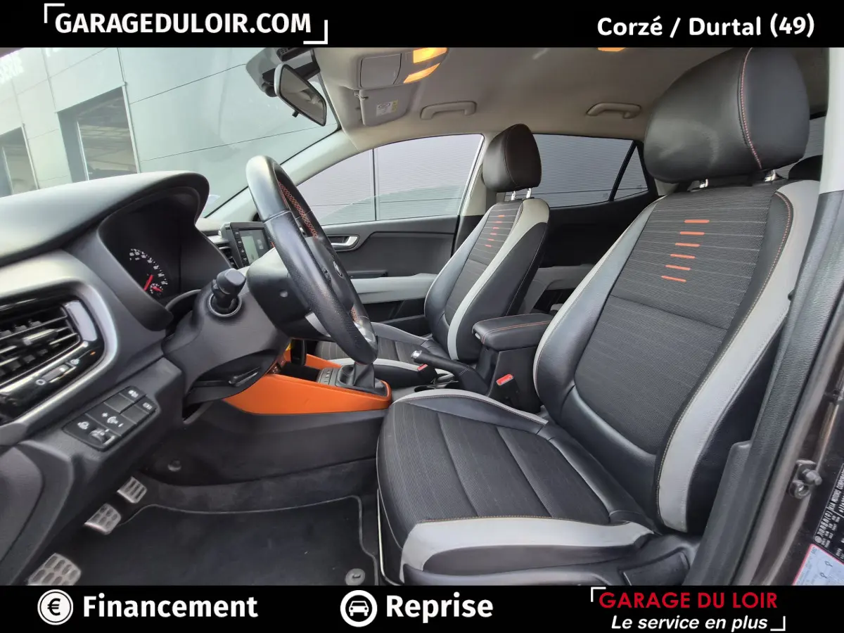 Vue intérieure côté conducteur de la Kia Stonic 1.0 T-GDi 2019 avec sièges noirs et détails orange sur console centrale.