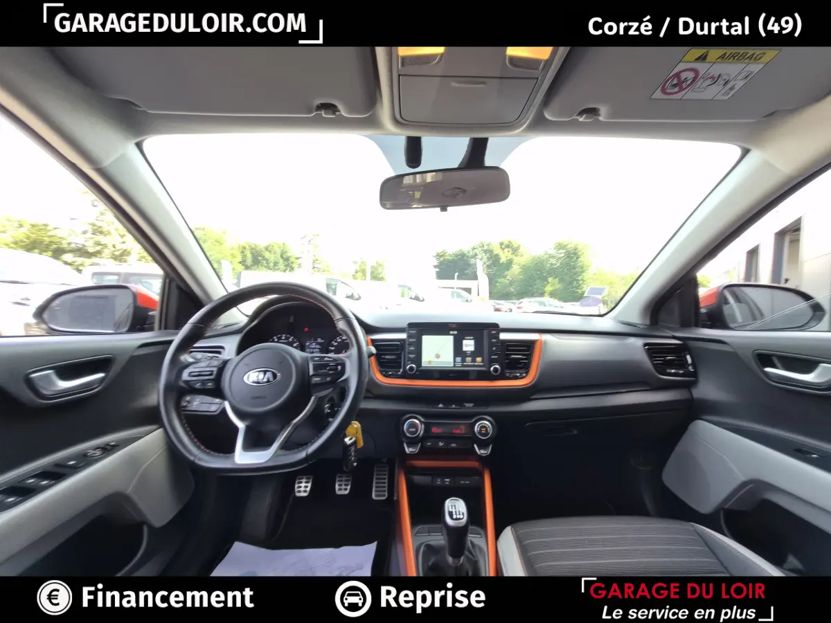 Vue intérieure avant du Kia Stonic 2019, tableau de bord noir avec inserts orange et volant multifonctions cuir.