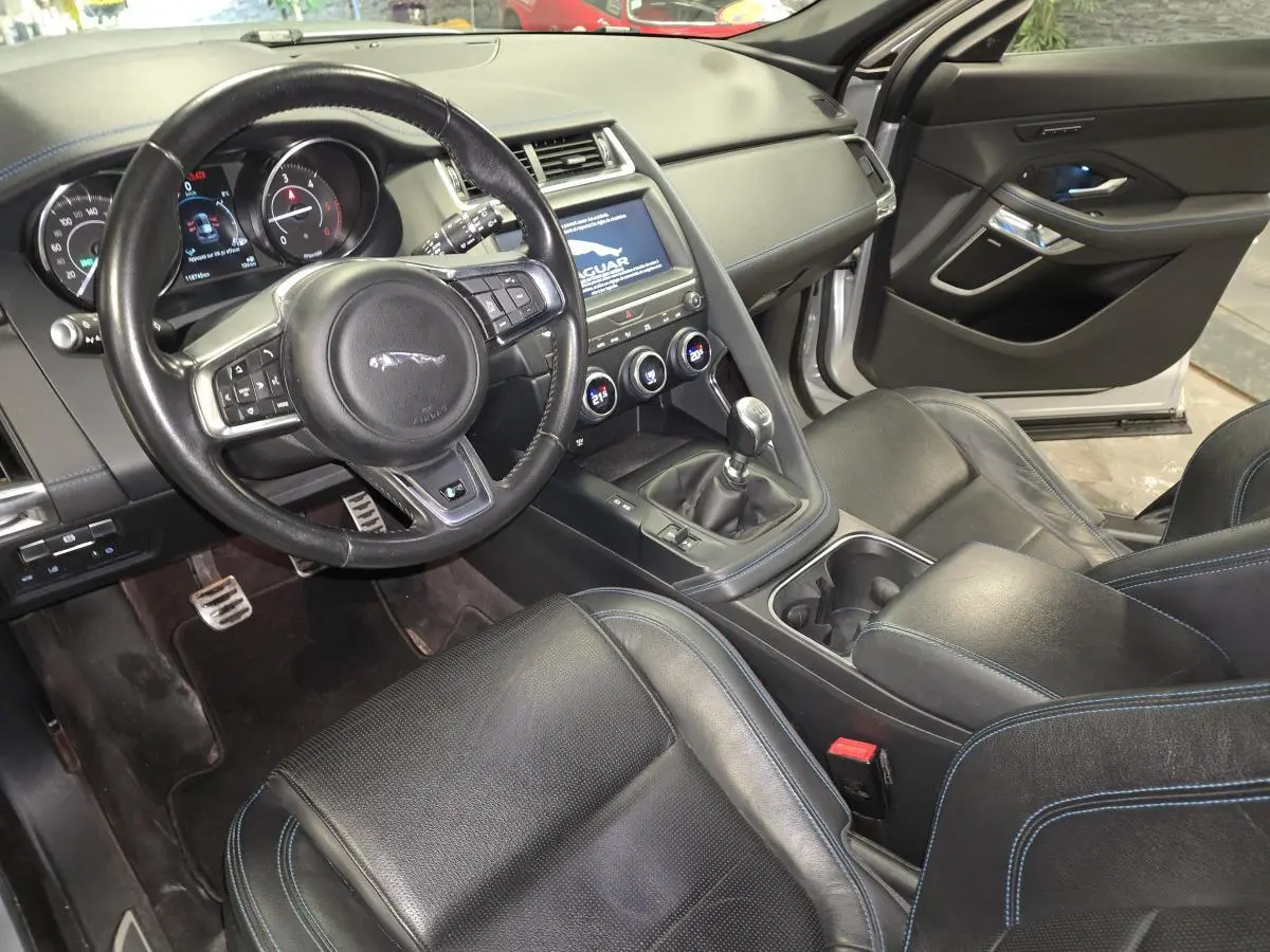 Vue intérieure côté conducteur de la Jaguar E-PACE D150 AWD R-Dynamic S 2019, sièges cuir noirs avec surpiqûres bleues.