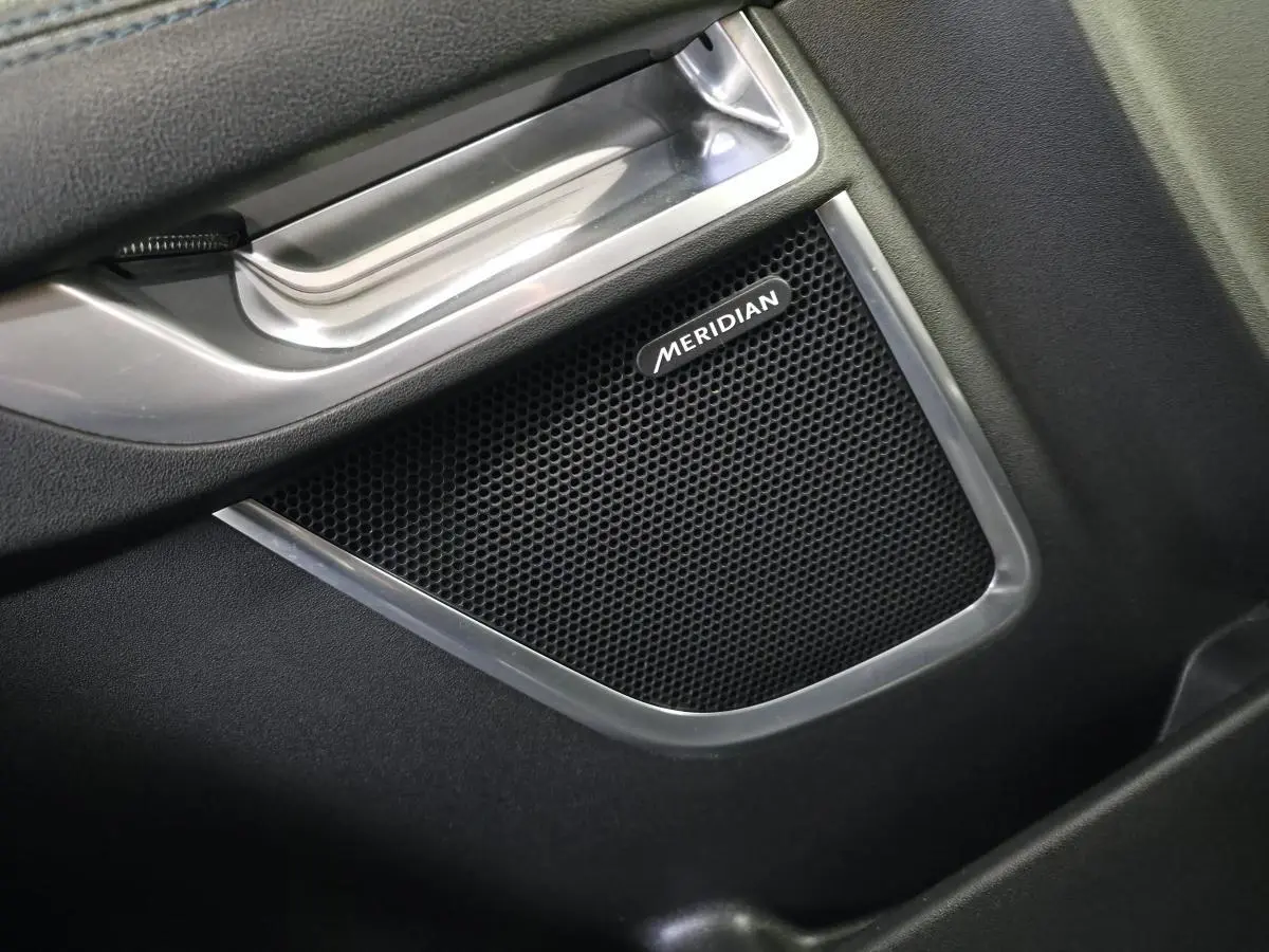 Gros plan sur l'enceinte Meridian intégrée à la porte intérieure côté conducteur du Jaguar E-PACE gris 2019.