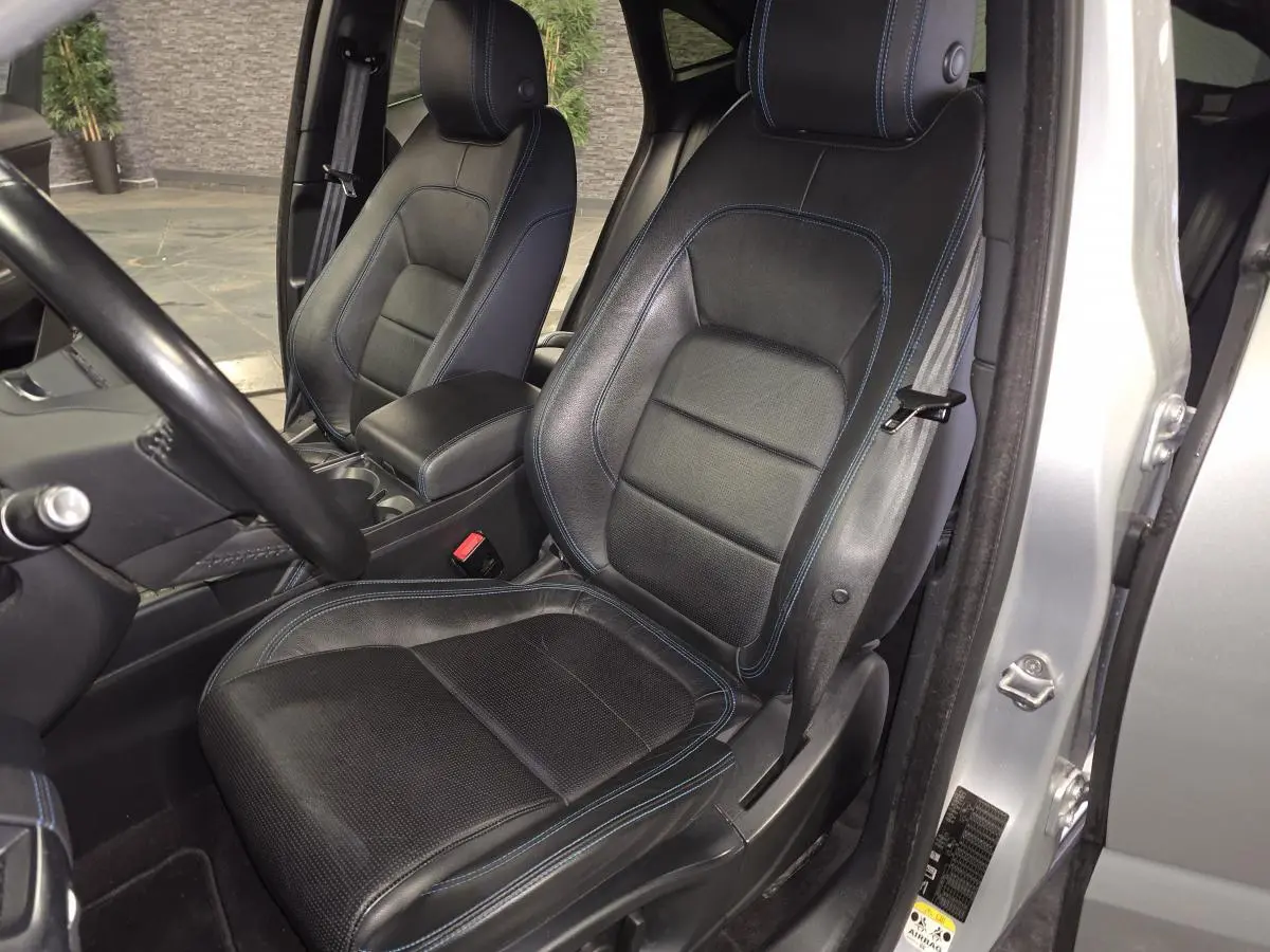 Vue intérieure côté conducteur des sièges sport en cuir noir avec surpiqûres bleues du Jaguar E-PACE gris 2019.