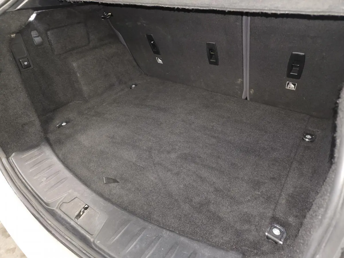 Coffre spacieux et propre du Jaguar E-PACE D150 AWD R-Dynamic S, vue intérieure avec moquette noire.