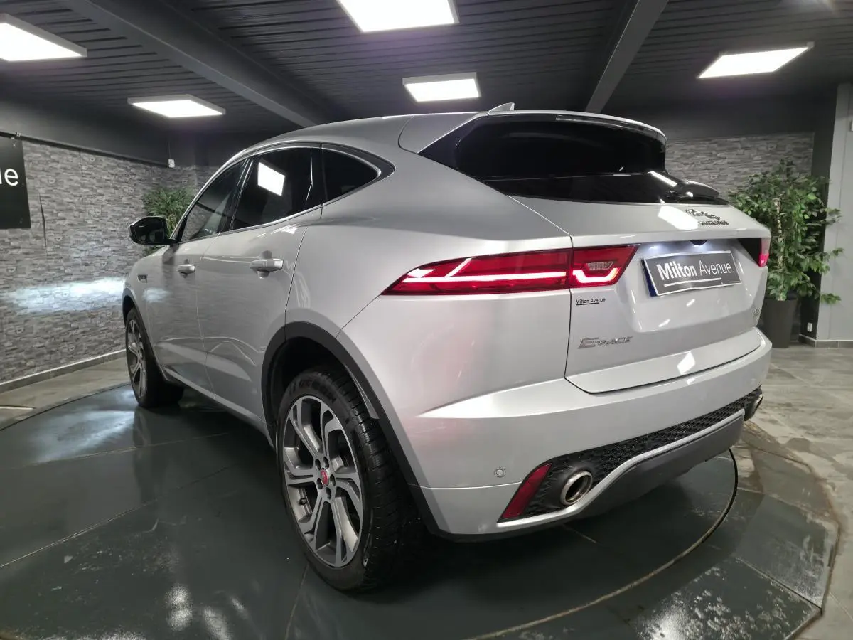 Jaguar E-PACE gris métallisé en 3/4 arrière droit, avec jantes 20 pouces et feux arrière LED distinctifs.