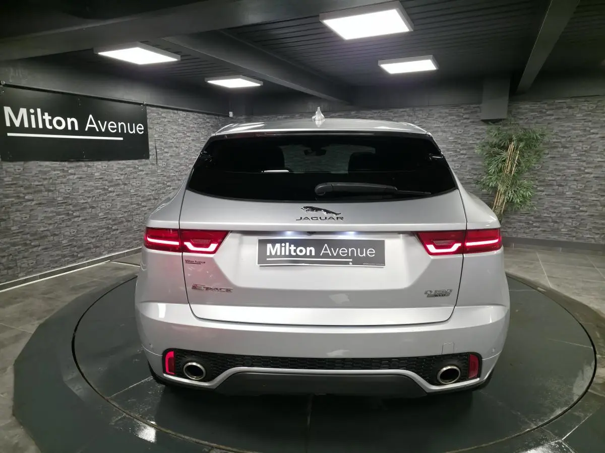 Vue arrière d'un Jaguar E-Pace gris métallisé 2019 avec feux LED et doubles sorties d'échappement visibles.