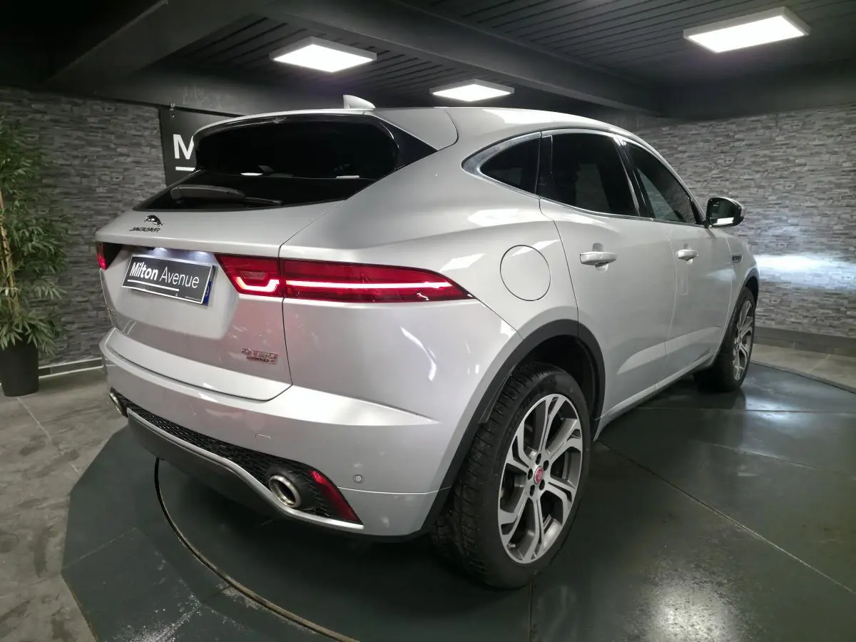 Vue 3/4 arrière droite d’un Jaguar E-PACE gris métallisé avec feux arrière LED et jantes 20 pouces à 6 branches doubles.