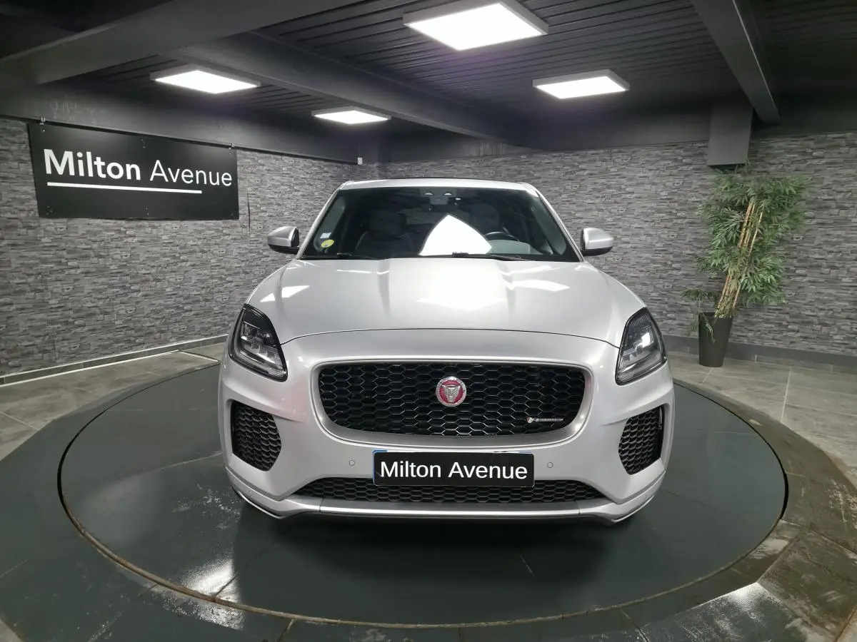 Jaguar E-PACE gris vue de face en intérieur, calandre noire avec logo Jaguar et phares LED marquants.