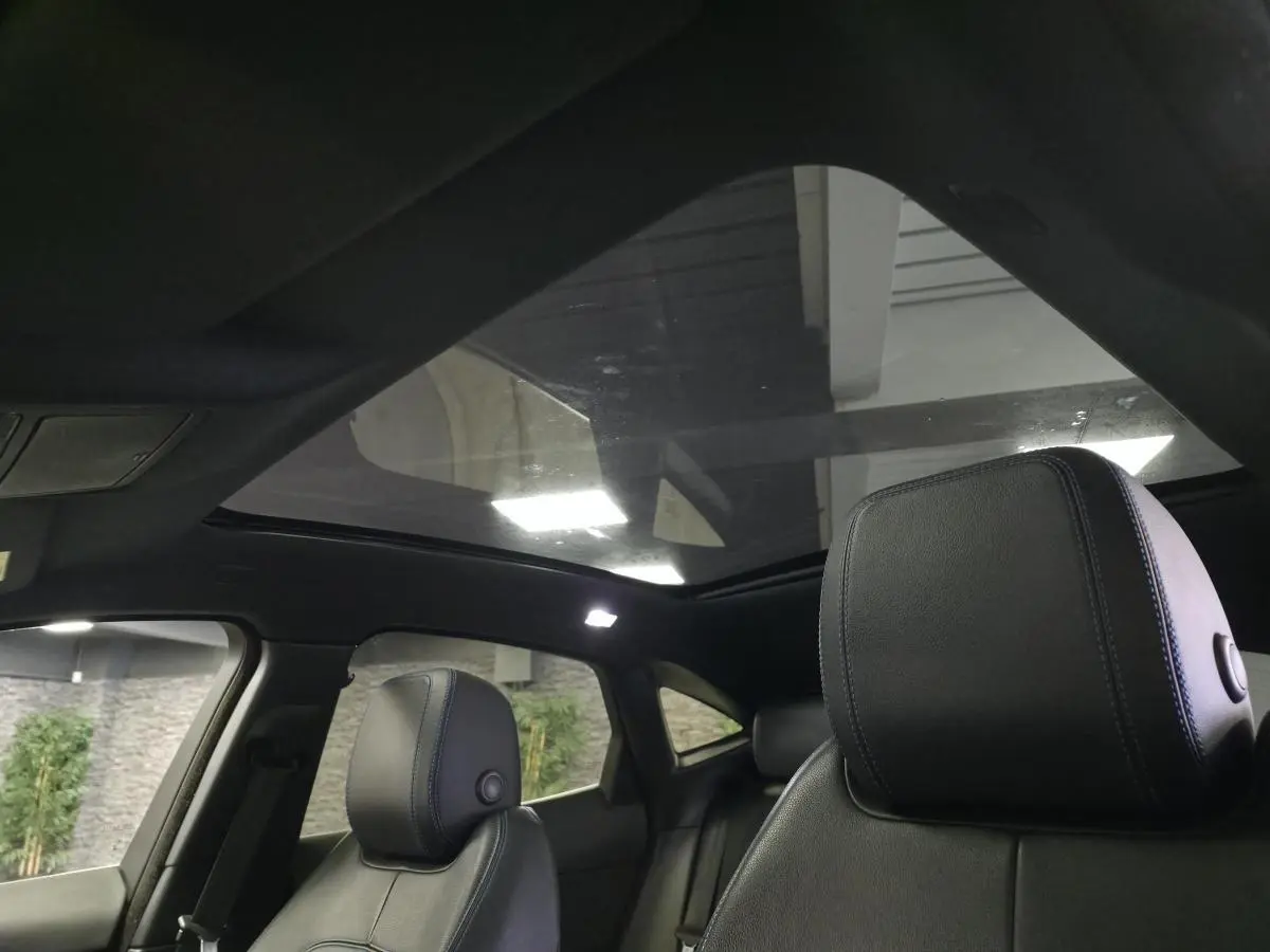 Intérieur du Jaguar E-PACE gris, vue sur les sièges avant en cuir noir et le toit panoramique fixe.
