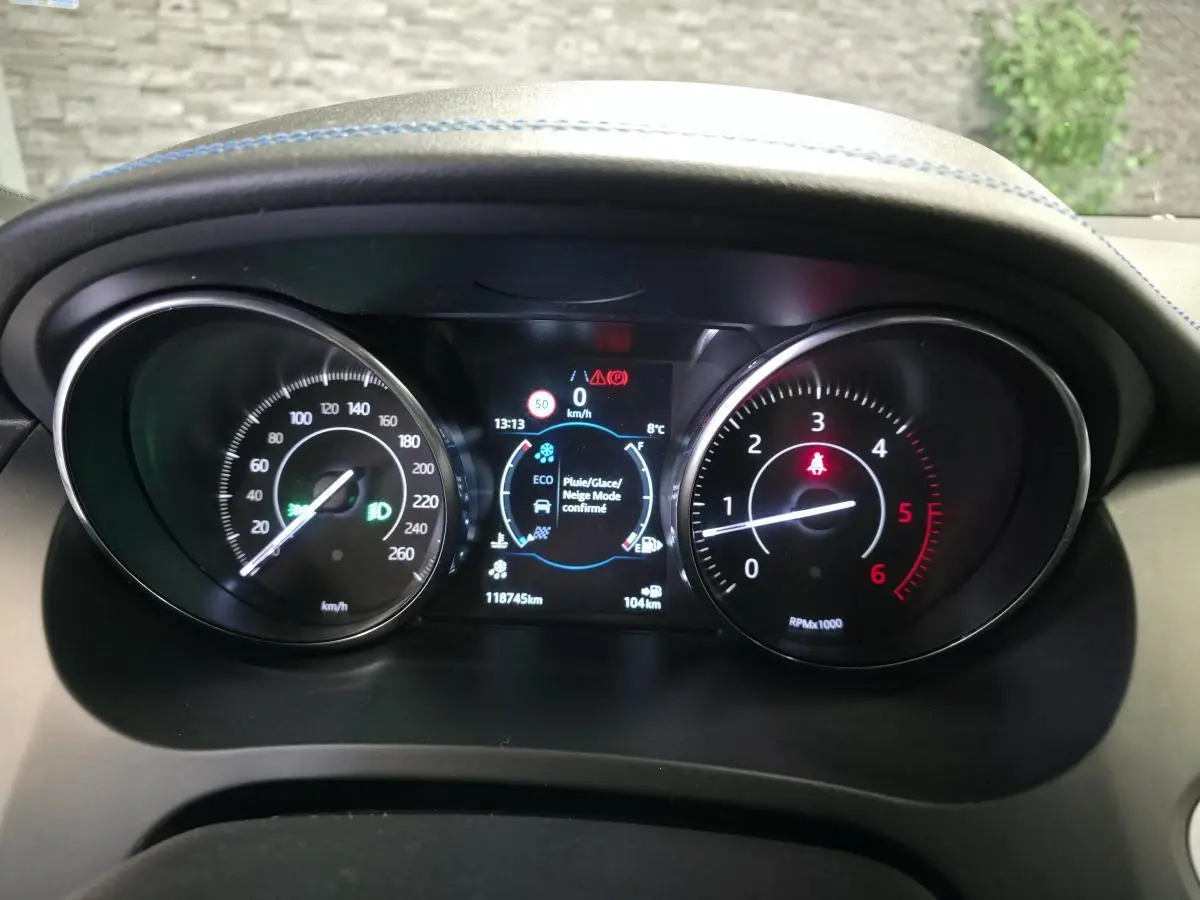 Vue rapprochée du tableau de bord noir du Jaguar E-PACE gris, affichant compteurs et écran digital central.