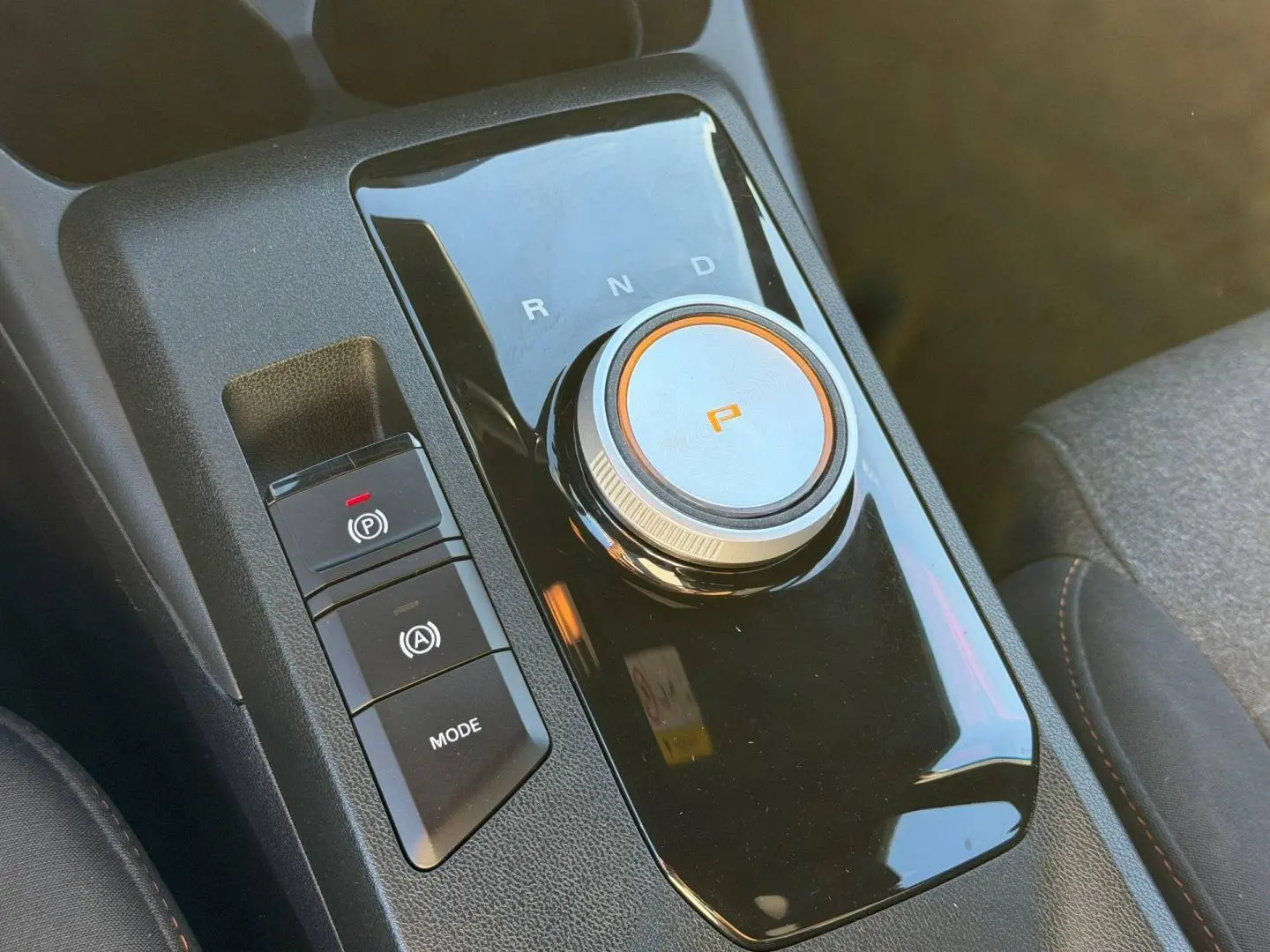 Gros plan sur la molette de boîte automatique noire avec indication "P" orange dans l’habitacle du MG3 2024.