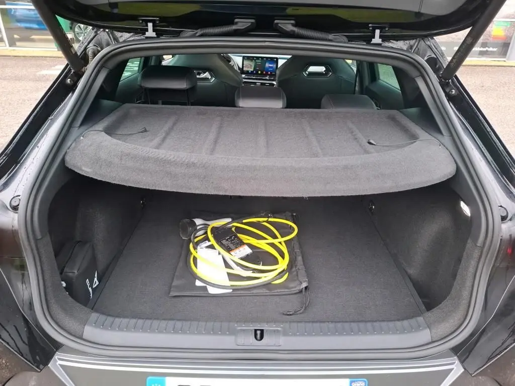 Coffre ouvert vu de l'arrière d'une CUPRA Formentor noir 1.4 E-HYBRID 245 VZ avec câble de recharge jaune visible.