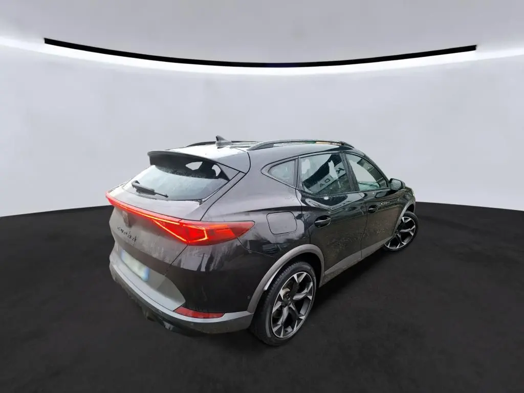 Vue 3/4 arrière droite d'une CUPRA Formentor 1.4 E-HYBRID 245 VZ noire avec feux arrière LED allumés.