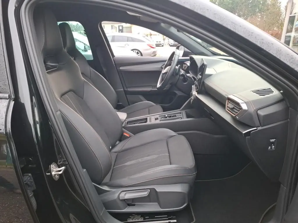 Vue intérieure côté conducteur de la CUPRA Formentor noir 2023, sièges tissu noirs et tableau de bord moderne.