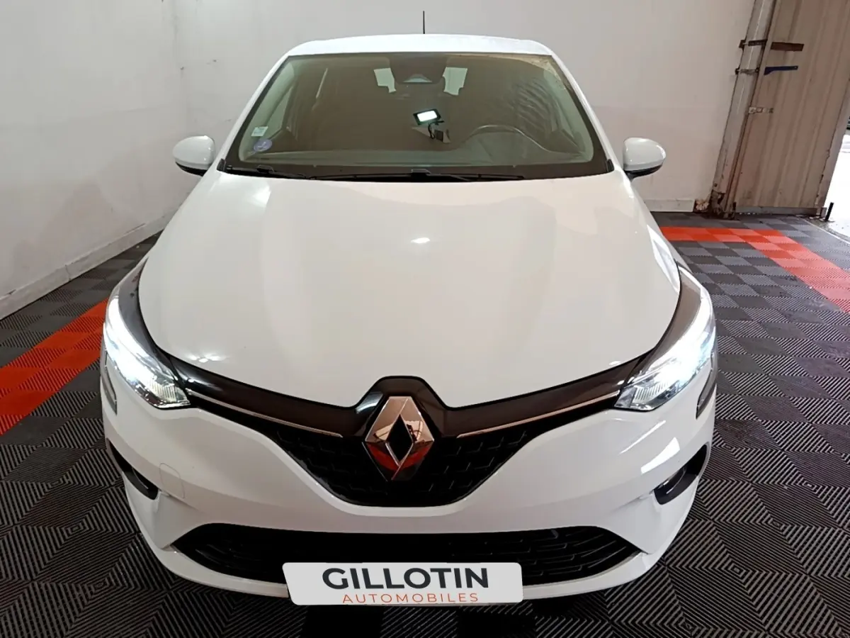 Vue avant d'une Renault Clio Business TCe 100 blanche avec phares LED allumés dans un garage.