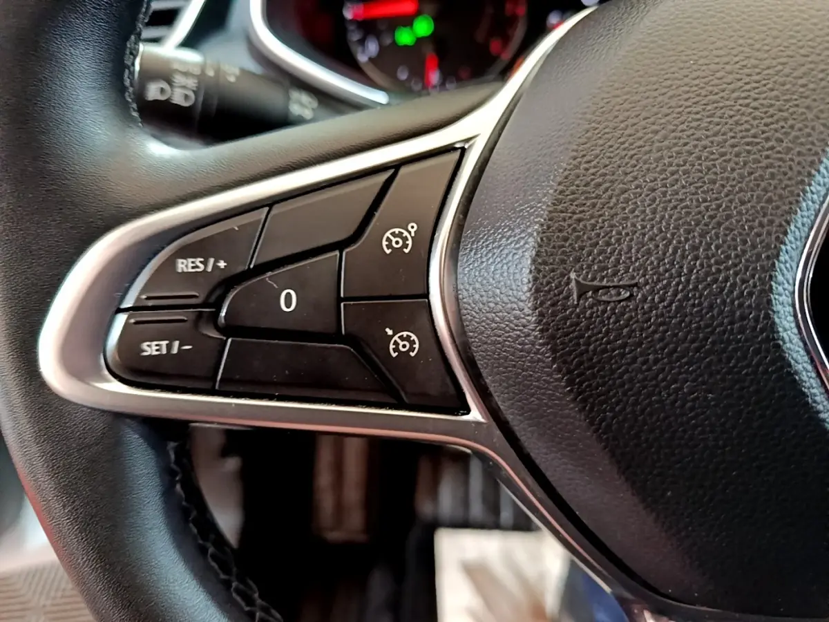 Gros plan sur le côté gauche du volant cuir synthétique noir de la Renault Clio Business TCe 100 2020 avec commandes de régulateur.