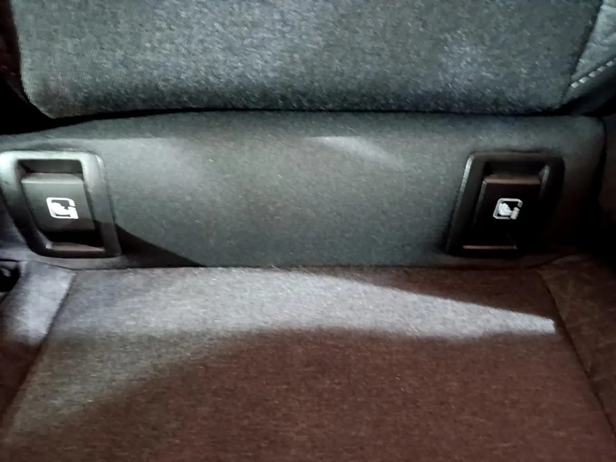 Détail des commandes de rabattement des sièges arrière sur la banquette d'une Renault Clio Business blanche.