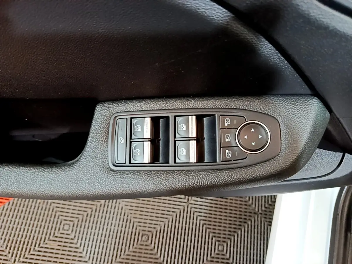 Vue rapprochée des commandes électriques des vitres sur la porte côté gauche d’une Renault Clio Business blanche.