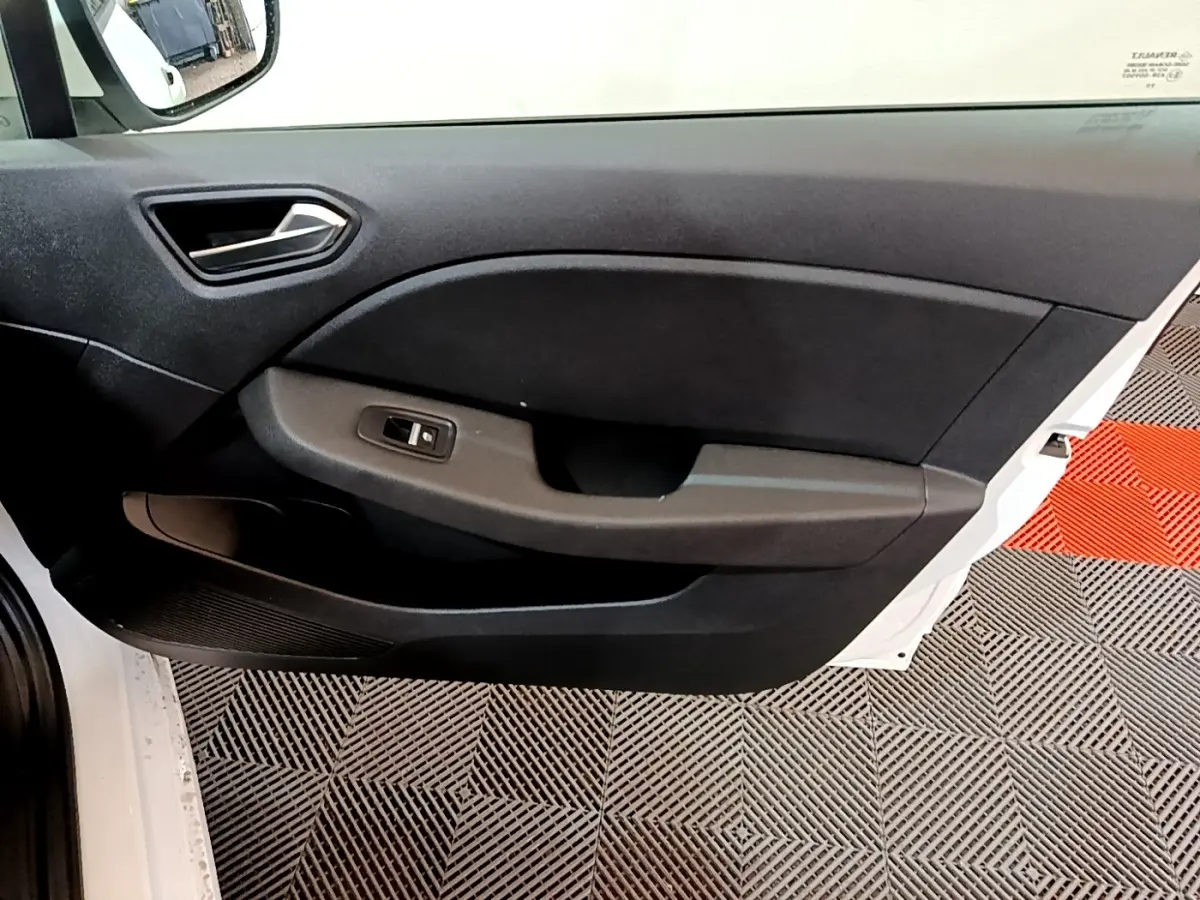 Vue intérieure côté gauche de la porte avant blanche d'une Renault Clio Business TCe 100, avec panneau noir et commande de vitre.