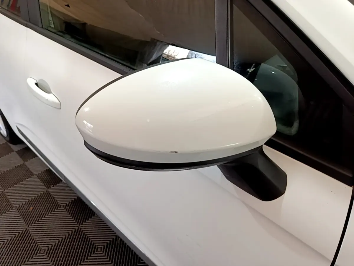 Gros plan sur le rétroviseur côté gauche blanc d'une Renault Clio Business TCe 100 de 2020, avec porte et vitre partiellement visibles.