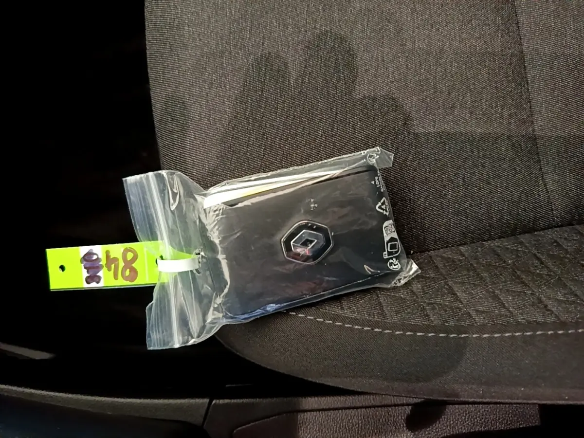 Clé Renault dans un sachet plastique posée sur un siège tissu gris foncé à l'intérieur d'une Clio blanche.
