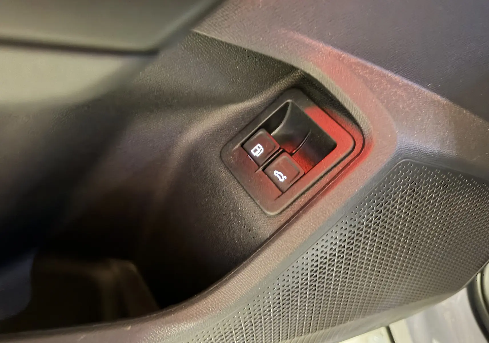 Détail des boutons d’ouverture de la trappe à carburant et du coffre sur la porte intérieure noire du CUPRA Formentor 1.4 Hybrid 245 VZ.