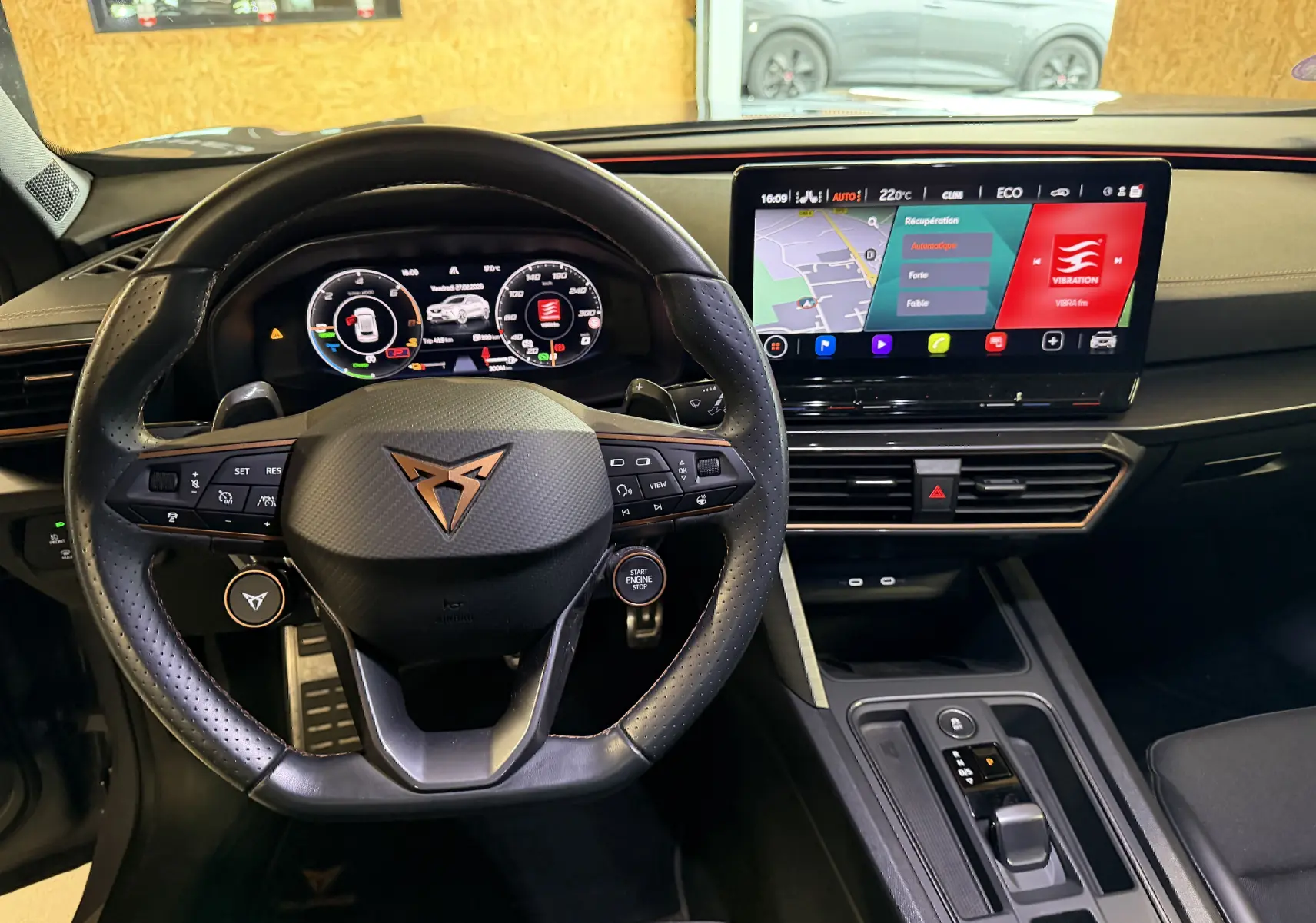 Vue intérieure centrée sur le volant noir perforé et l'écran tactile du tableau de bord du CUPRA Formentor gris 2023.