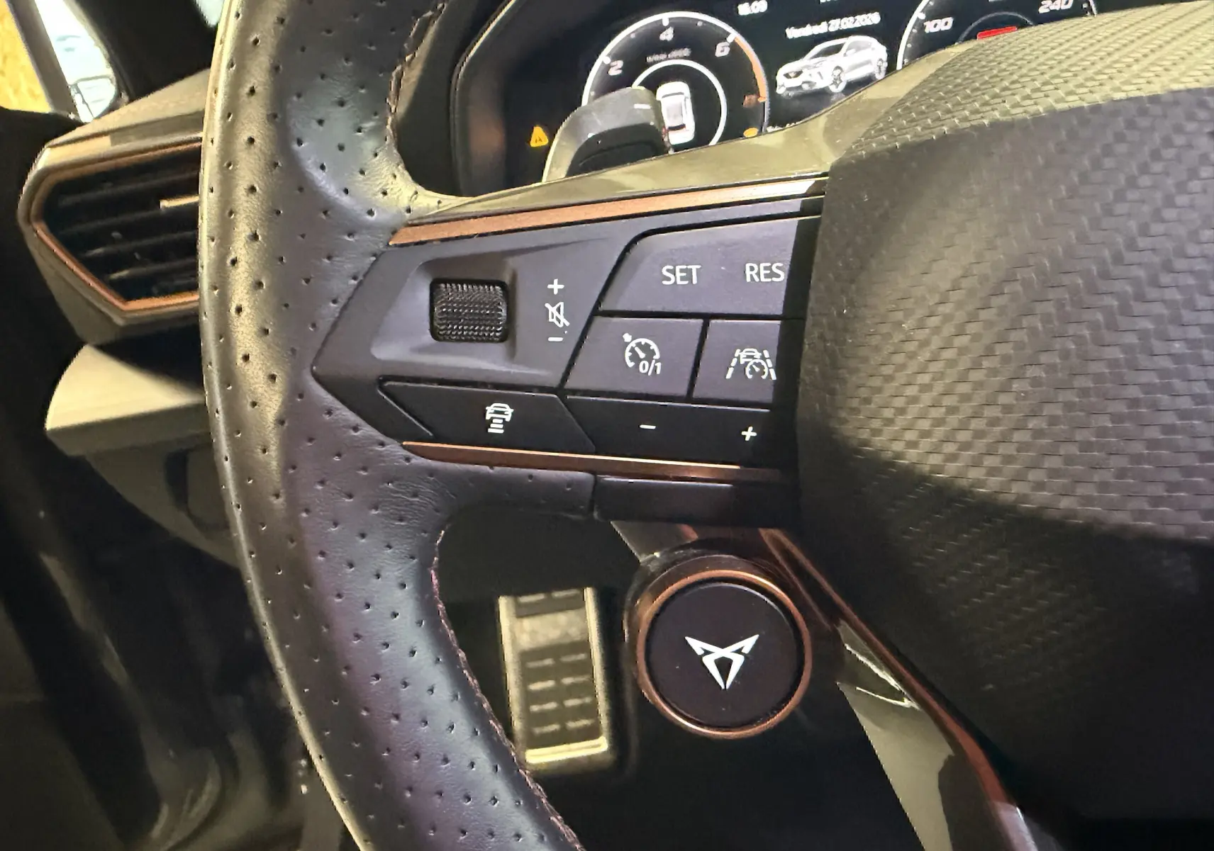 Gros plan sur le volant en cuir perforé noir du CUPRA Formentor 1.4 Hybrid 245 VZ avec commandes intégrées et logo distinctif.