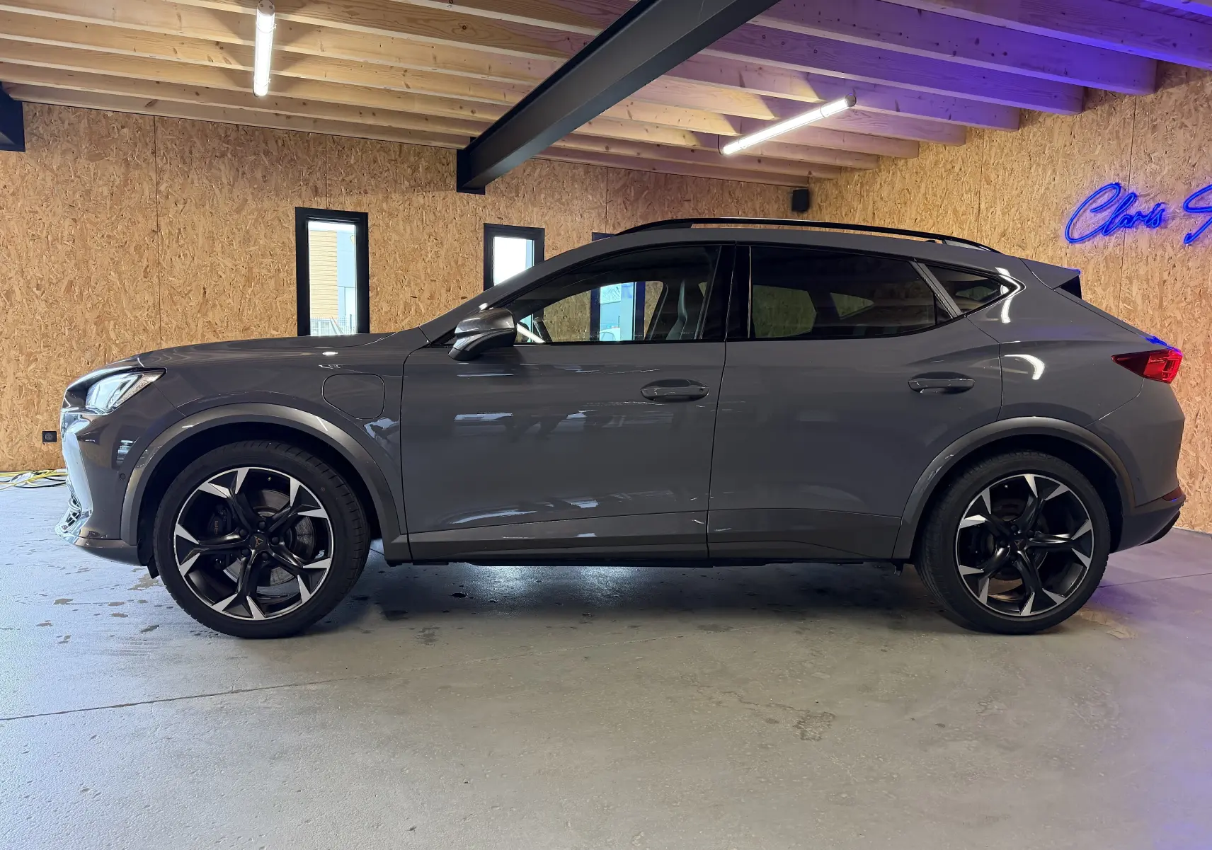 Vue de profil côté gauche du CUPRA Formentor gris 2023 hybride, avec jantes noires et toit ouvrant visible.