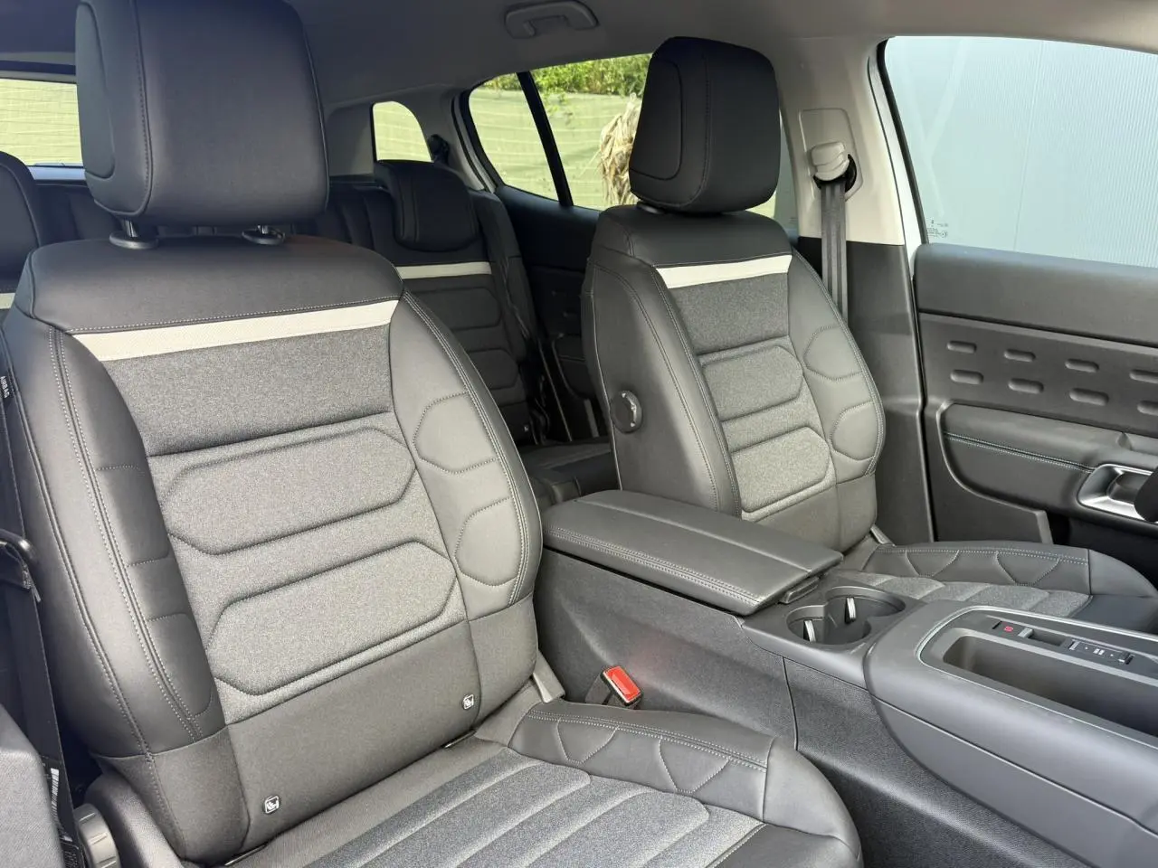 Vue intérieure côté droit des sièges avant gris foncé et tissu clair du Citroën C5 Aircross 2026 avec accoudoir central.
