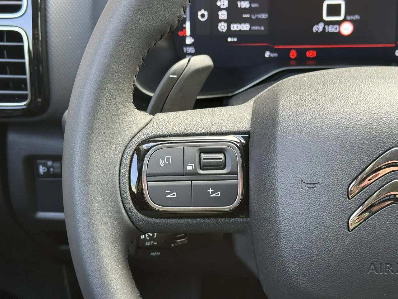 Gros plan sur le volant cuir noir du Citroën C5 Aircross 2026, avec commandes intégrées côté gauche et combiné numérique en arrière-plan.