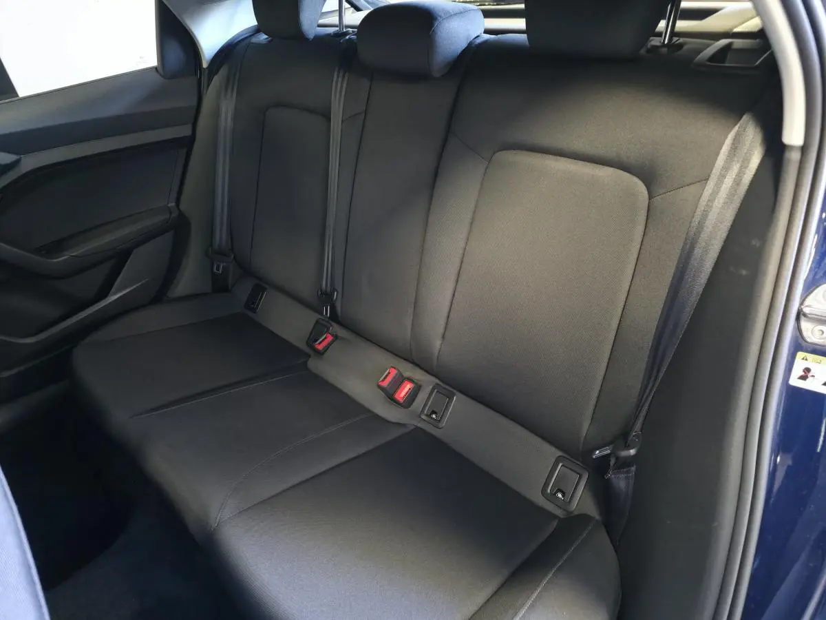 Vue latérale de la banquette arrière noire en tissu Novum de l'Audi A1 Sportback 2024 bleu, avec ceintures et appuie-têtes.