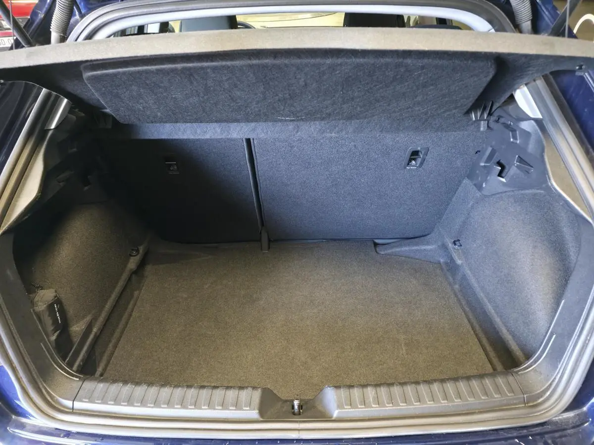 Coffre ouvert vu de l'arrière d'une Audi A1 Sportback bleu, montrant un espace de chargement propre et spacieux.