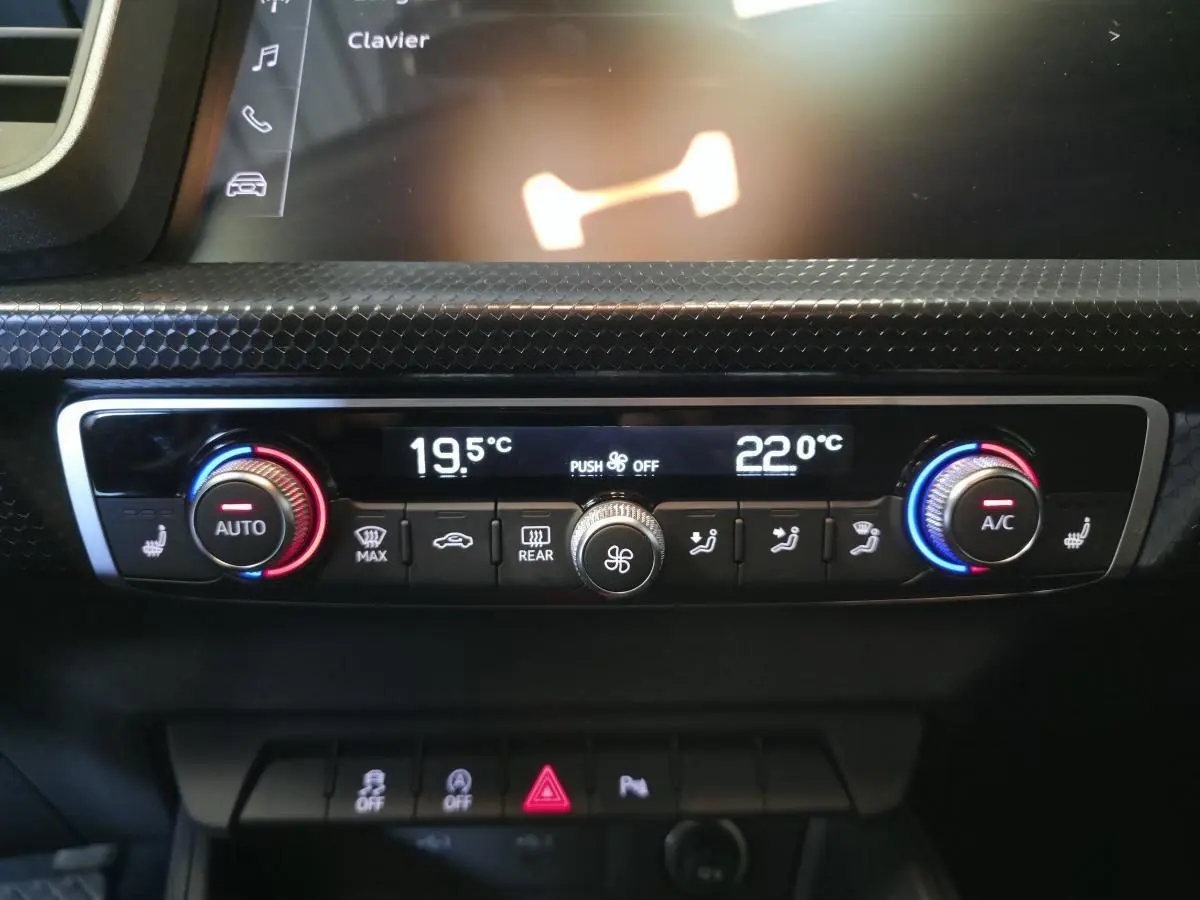 Panneau de climatisation automatique bi-zone de l’Audi A1 Sportback 2024 avec réglages numériques et boutons rotatifs colorés.