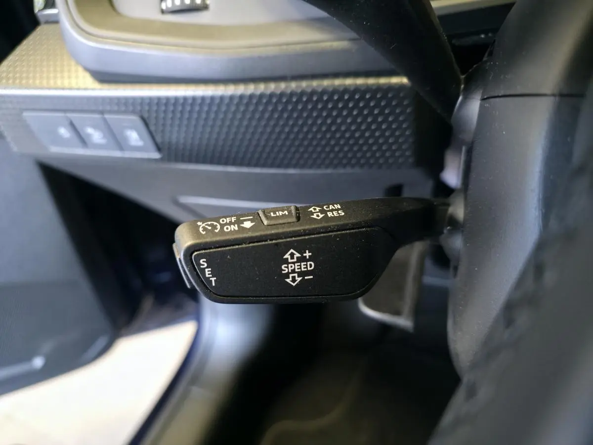 Gros plan sur le levier de régulateur de vitesse noir à gauche du volant dans l’Audi A1 Sportback 2024.