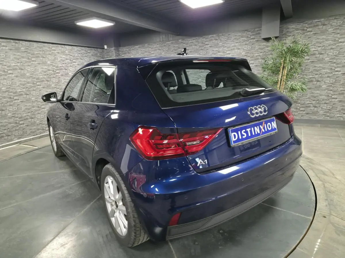 Audi A1 Sportback bleu métallisé vue 3/4 arrière droit, avec feux arrière LED et jantes aluminium 16 pouces.