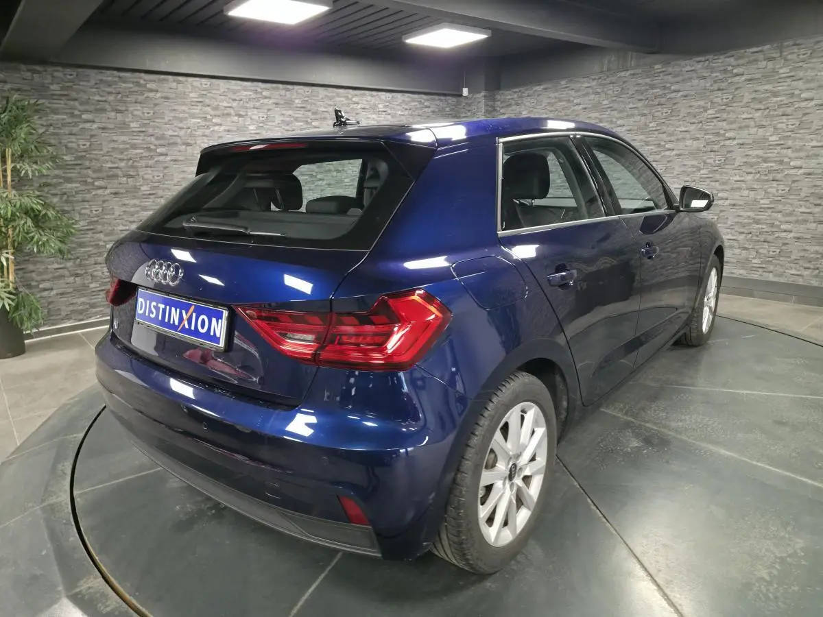 Audi A1 Sportback bleu métallisé vue 3/4 arrière droit en intérieur avec feux arrière LED et jantes 16 pouces.
