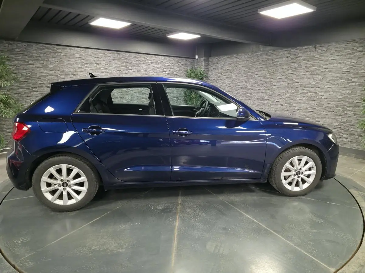 Audi A1 Sportback bleu métallisé vue de profil côté gauche dans un showroom avec jantes aluminium 16 pouces.