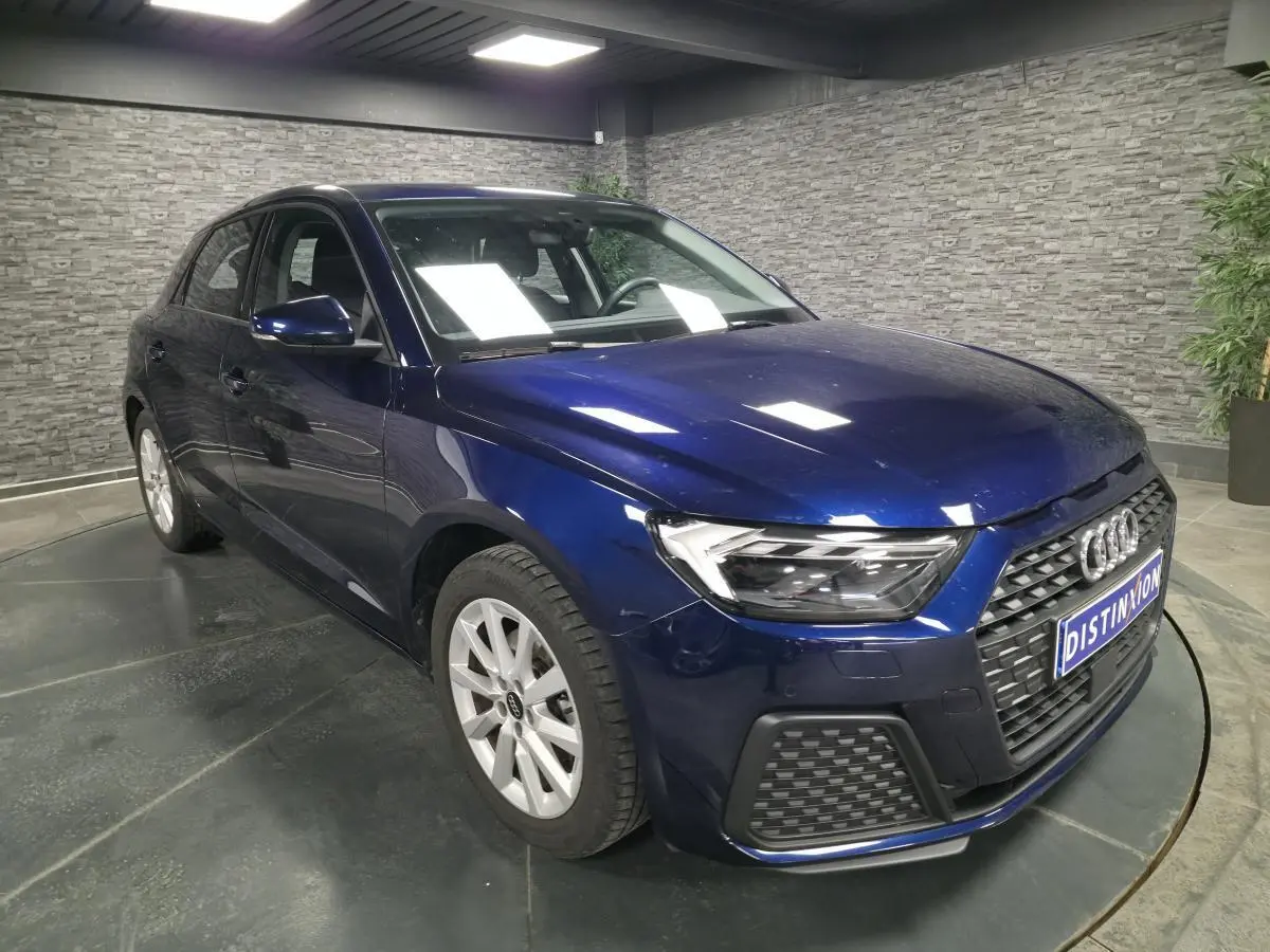 Audi A1 Sportback bleu métallisé vue 3/4 avant droit, calandre noire et jantes alu 16 pouces visibles.