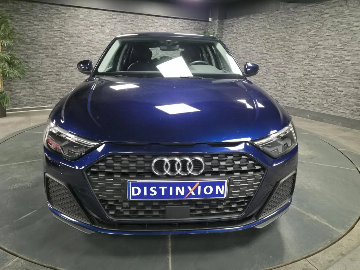 Vue avant d'une Audi A1 Sportback 2024 bleu métallisé avec calandre noire et phares LED distinctifs.